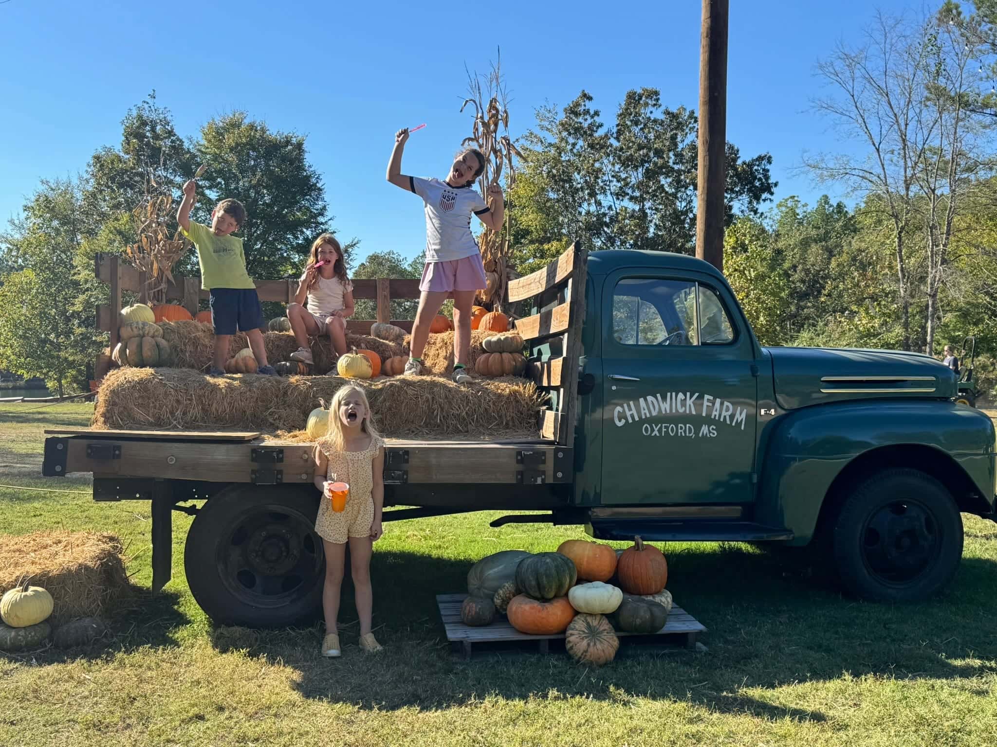 Kids smiling on the vintage Chadwick Farm truck with hay and fall decorations