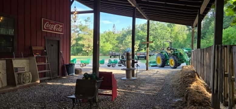 Green tractor parked inside the red barn