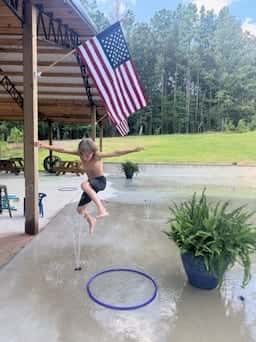 Child splashing through the spray at the splash pad