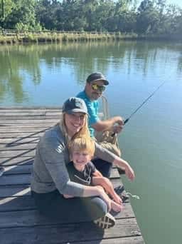 Adults and a child fishing from the pond dock
