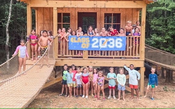 Class group gathered on a farm structure with a welcome banner
